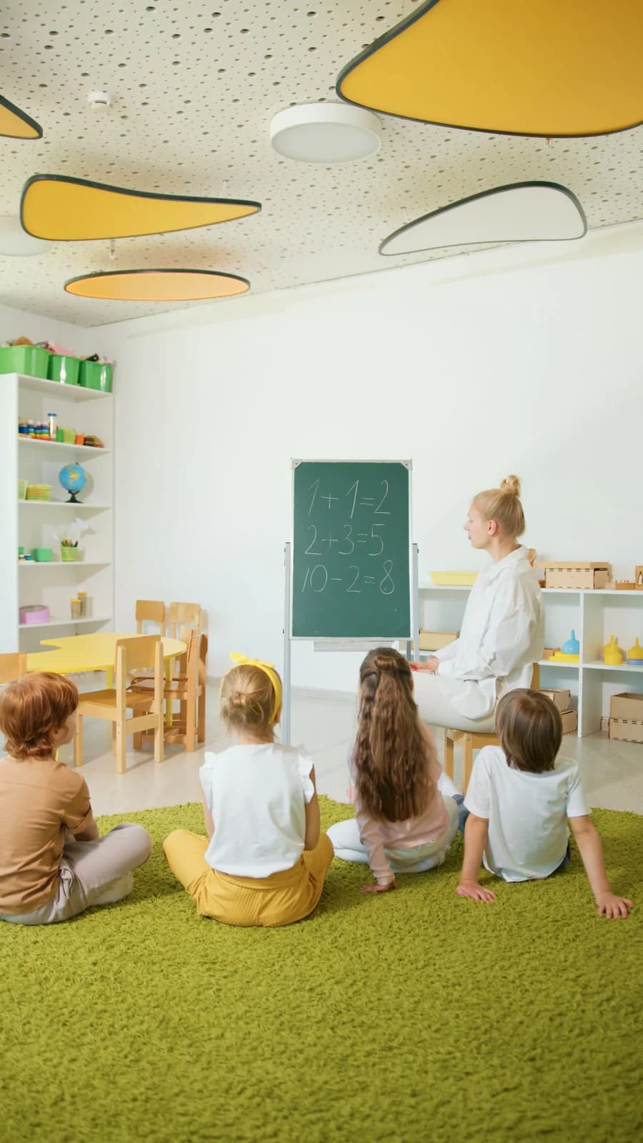 Teacher guiding younger students through a colorful math lesson